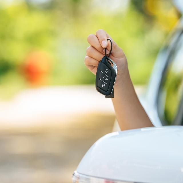 girl sitting in the car and holding the car keys hands out of the car.