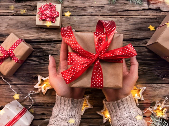 Top view of woman hands with gift box on wooden table.